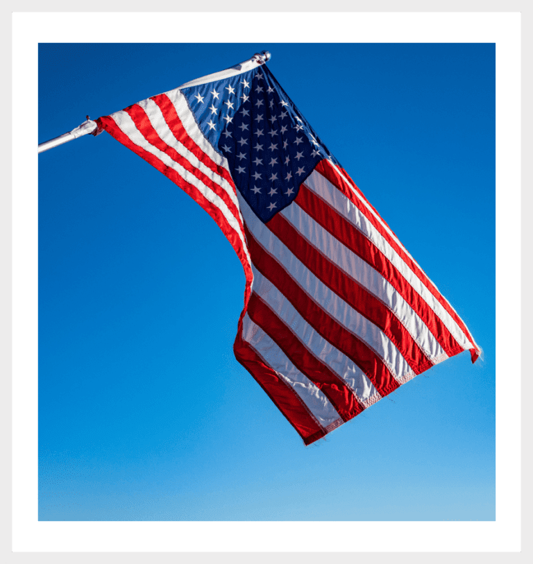 An American flag flying in the wind outside a house