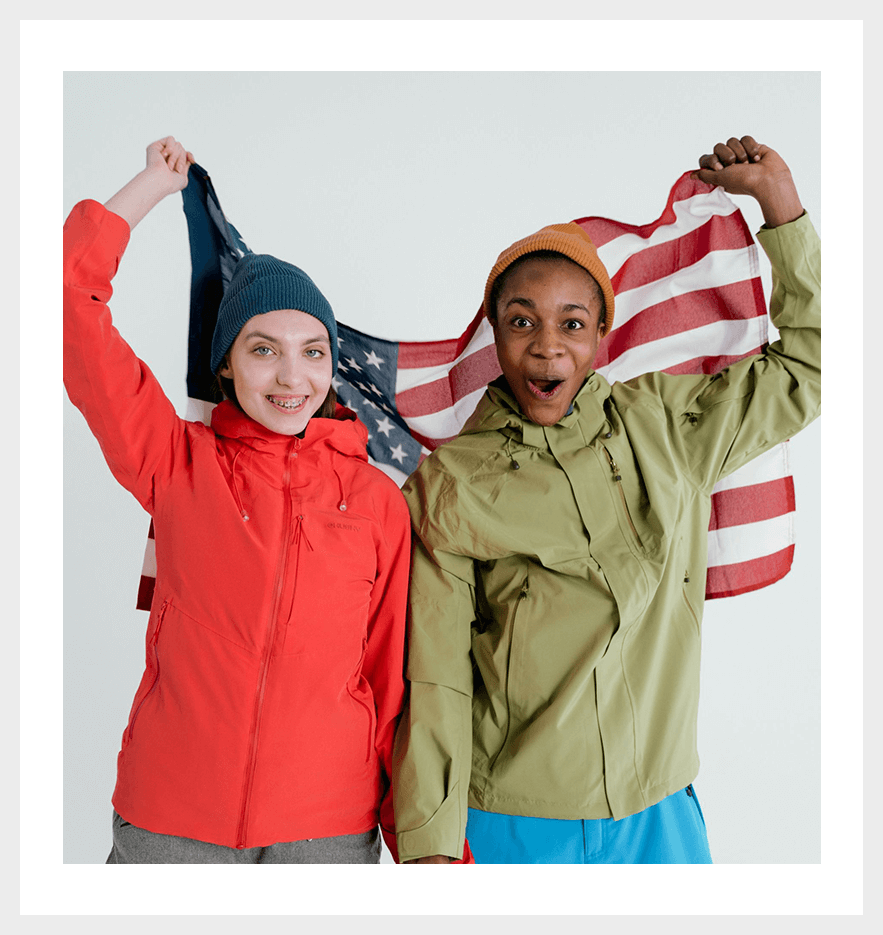 Two people holding up american flags in front of their faces.