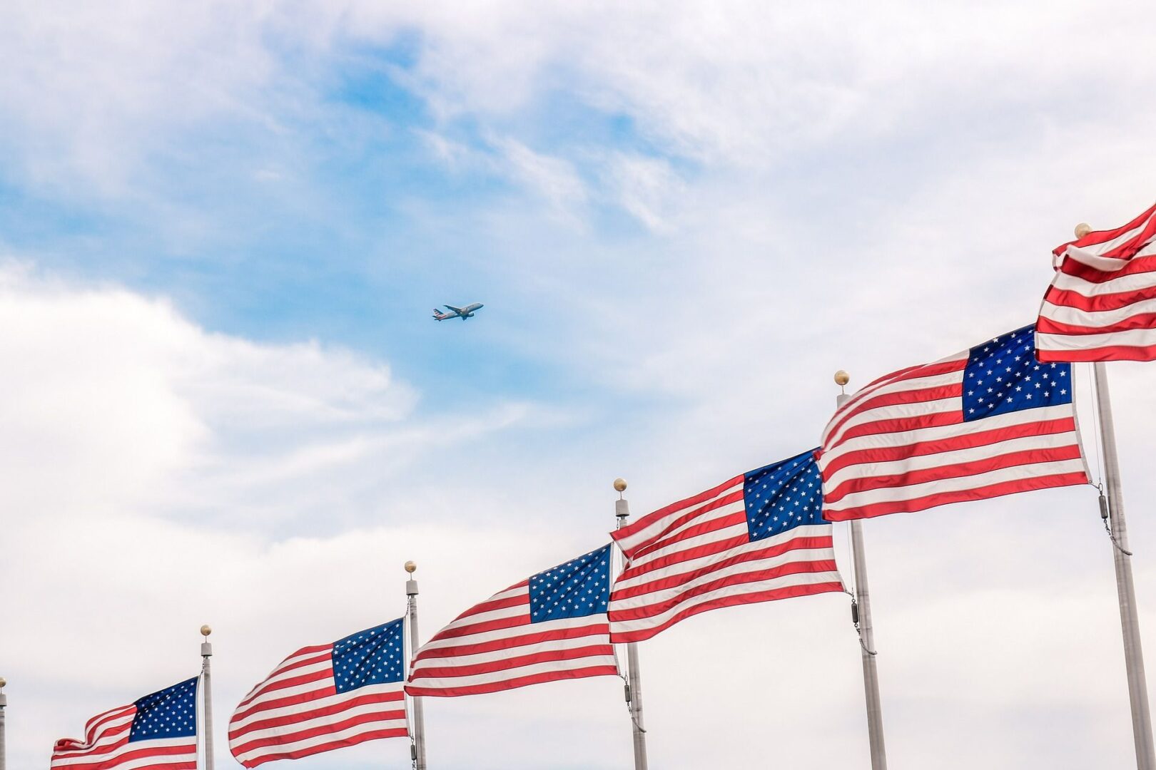 A line of american flags flying in the wind.