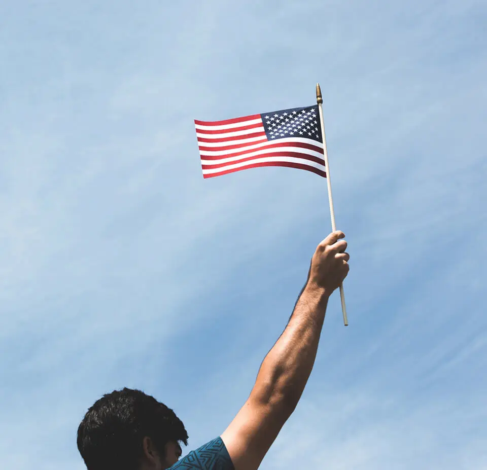 A person holding an american flag in the air.