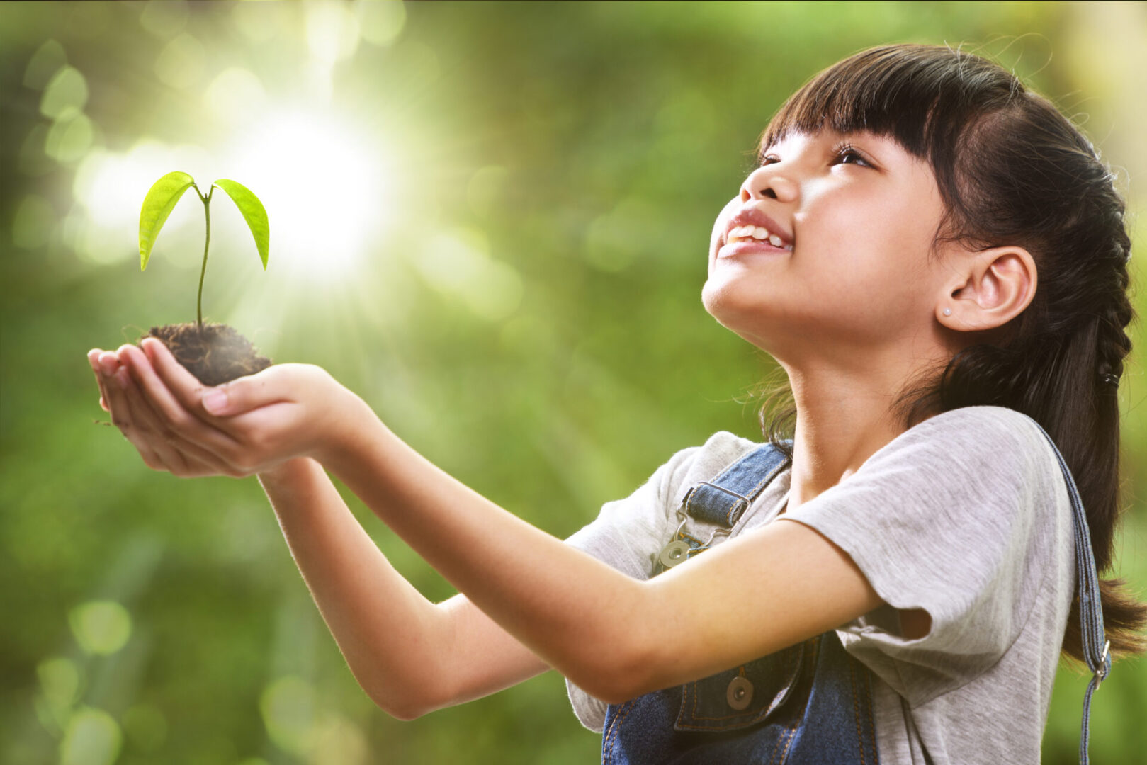 A young girl holding a plant in her hands.