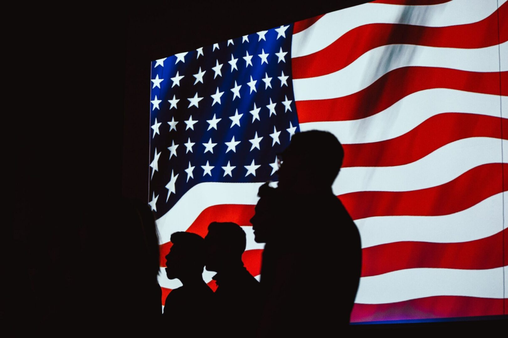 A couple is standing in front of an american flag.