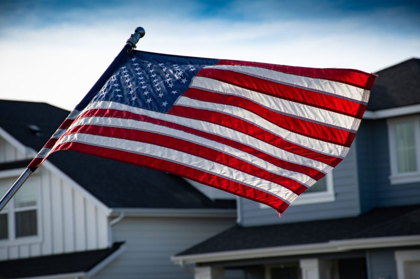 A flag is flying in the wind outside of a house.